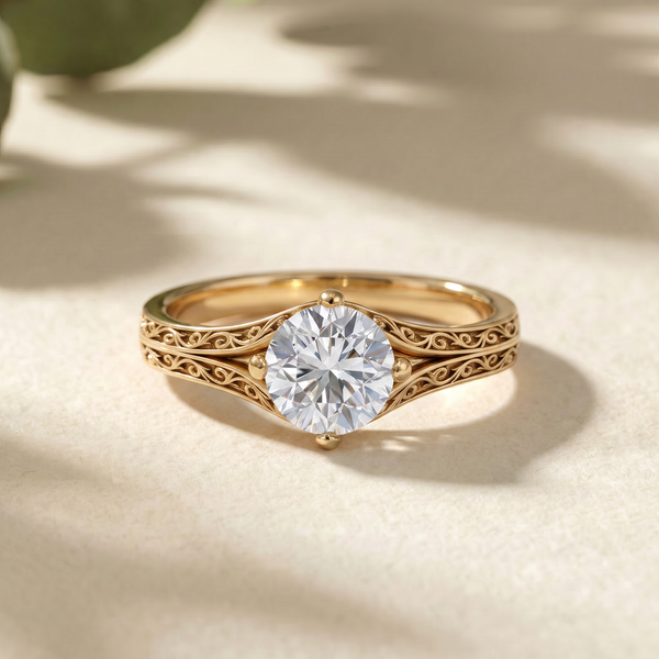 A gold ring with an ornate filigree band and a round brilliant-cut clear gemstone, photographed on a warm beige surface with soft leaf shadows.